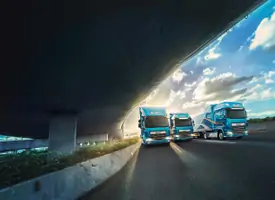 Different DAF Trucks driving on the road, below a bridge.